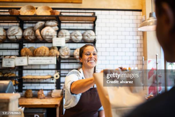 bakery owner giving food package to customer - restaurant owner stock pictures, royalty-free photos & images