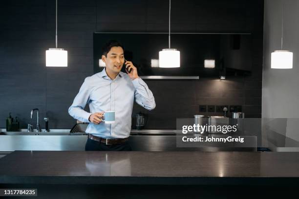 mature east asian executive working remotely - kitchen bench top stock pictures, royalty-free photos & images