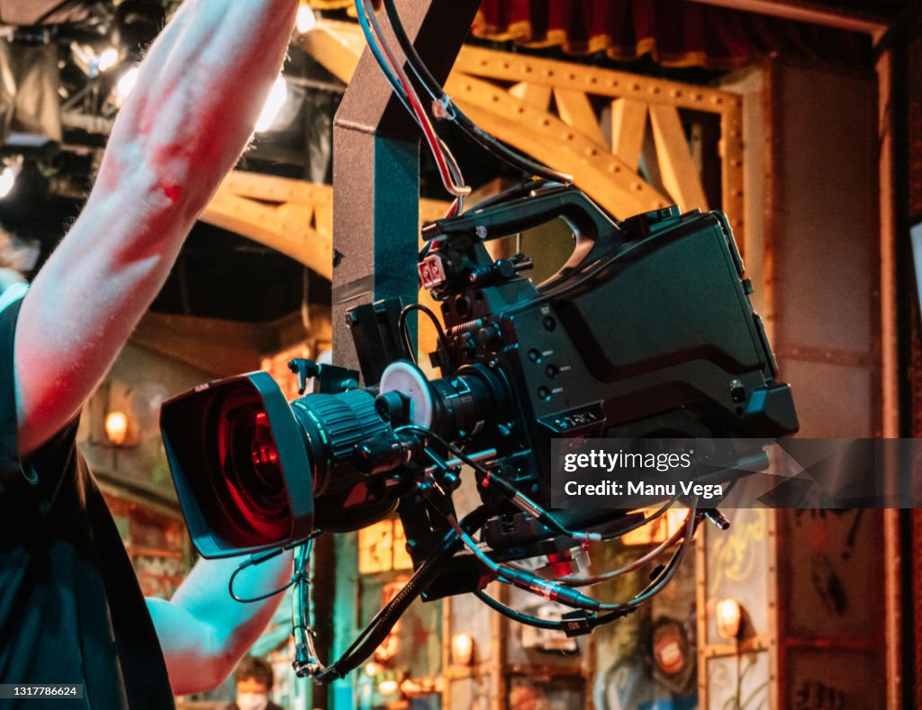 Rear view of a TV camera crane with an assistant in front of it in a TV studio.