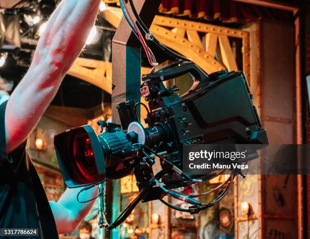 rear view of a tv camera crane with an assistant in front of it in a tv studio. - film set crew stock pictures, royalty-free photos & images