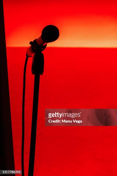 silhouette of a microphone with red light behind - silhouette auditorium stock pictures, royalty-free photos & images