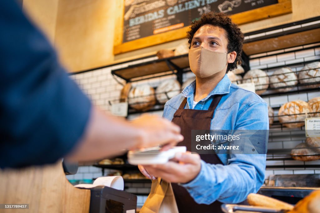 Waitress accepting mobile payment from a customer at bakery