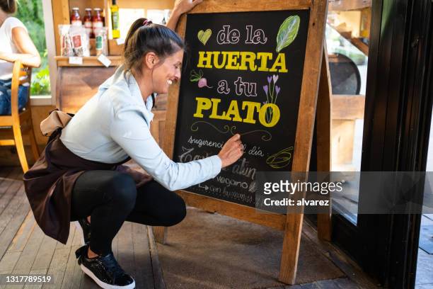 cafe owner writing special menu on the chalkboard - chalkboard menu stock pictures, royalty-free photos & images