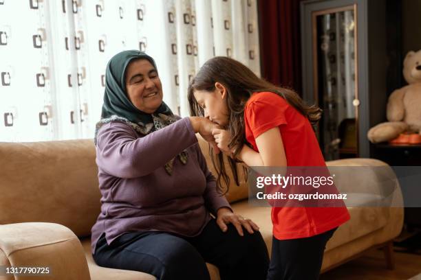 little girl kissing grandmother's hand in ramadan a religious festival in turkey - ramadan family stock pictures, royalty-free photos & images