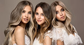 Three young attractive models  is demonstrating professionally dyed long hair. Elegance, hairstyling and makeup.