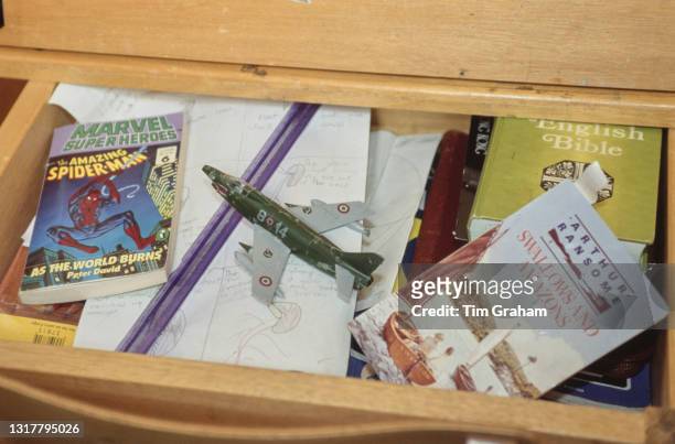 Flip-top desk with the lid up, revealing a paperback edition of 'Marvel Super Heroes: The Amazing Spider-Man - As The World Burns', by Peter David, a...