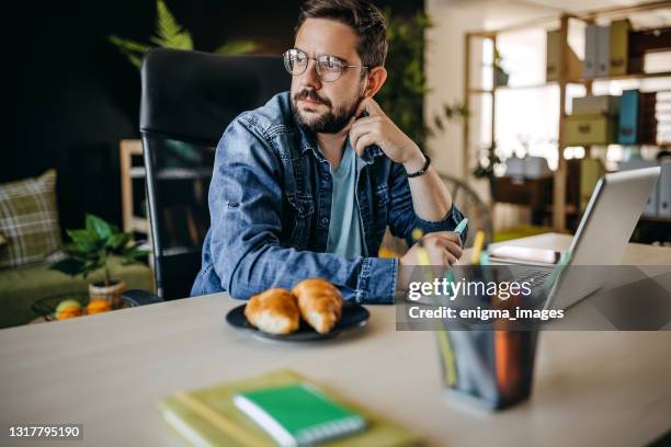 cheerful male freelancer in eyeglasses sitting at work desktop while using laptop - video reviewed stock pictures, royalty-free photos & images