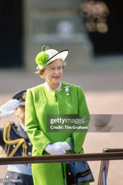British Royal Queen Elizabeth II, wearing a green coat and a white hat with black trim and a green pom-pom, during a fly-past and parade...
