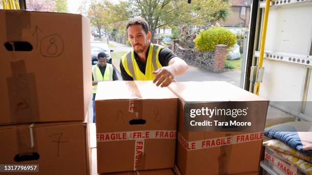 delivery men unloading boxes from van - lossen stockfoto's en -beelden