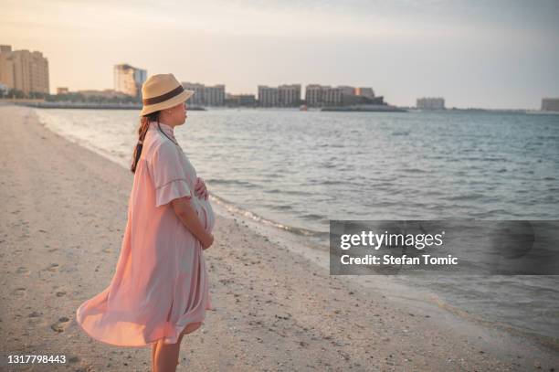 mujer embarazada en la playa junto al mar al atardecer - hot arabian women fotografías e imágenes de stock