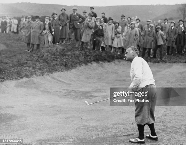 Specatators look on as Cyril Tolley of England smoking a cigarette plays a chip shot out of the sand bunker during the English Amateur Golf...