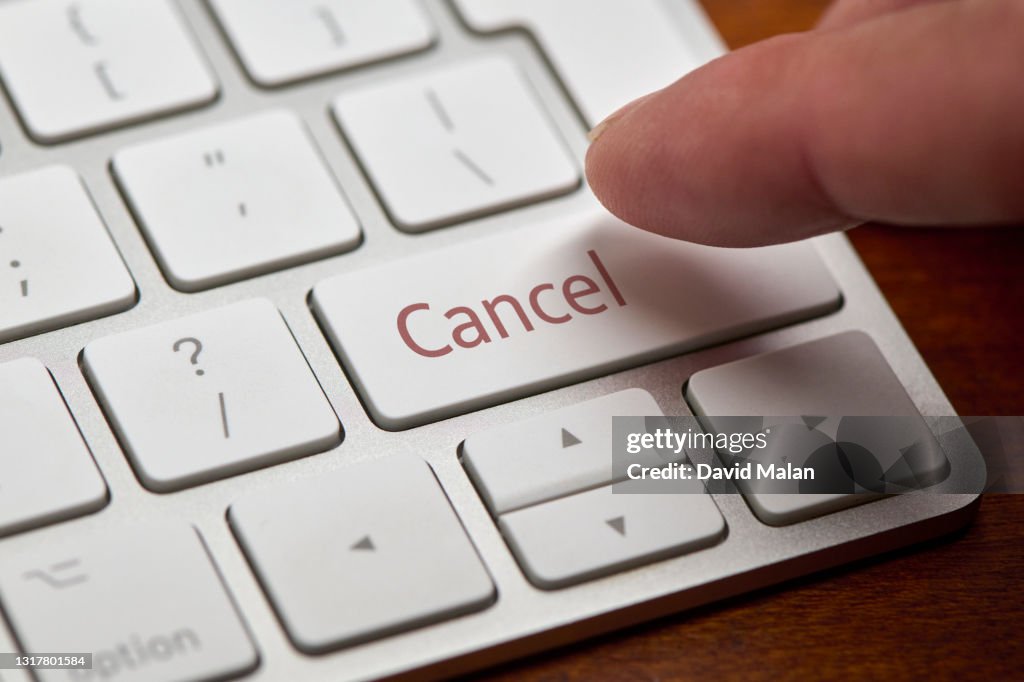 A finger about to press a "Cancel" button on a computer keyboard.