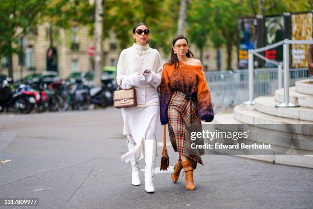 Gabriella Berdugo wears sunglasses, necklaces, a cream color hi-neck sweater, a light mauve vest, a light mauve asymmetric skirt, a Carolina Herrera...