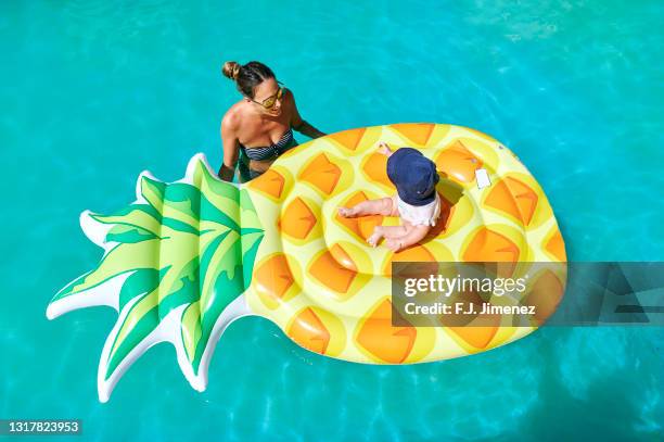 mother with her baby on float in the pool - inflatable pool toys imagens e fotografias de stock