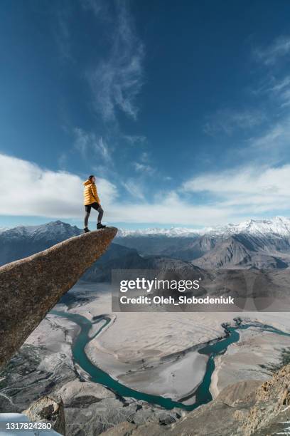 woman standing on the edge of hanging rock above the river - mountain peak above clouds stock pictures, royalty-free photos & images