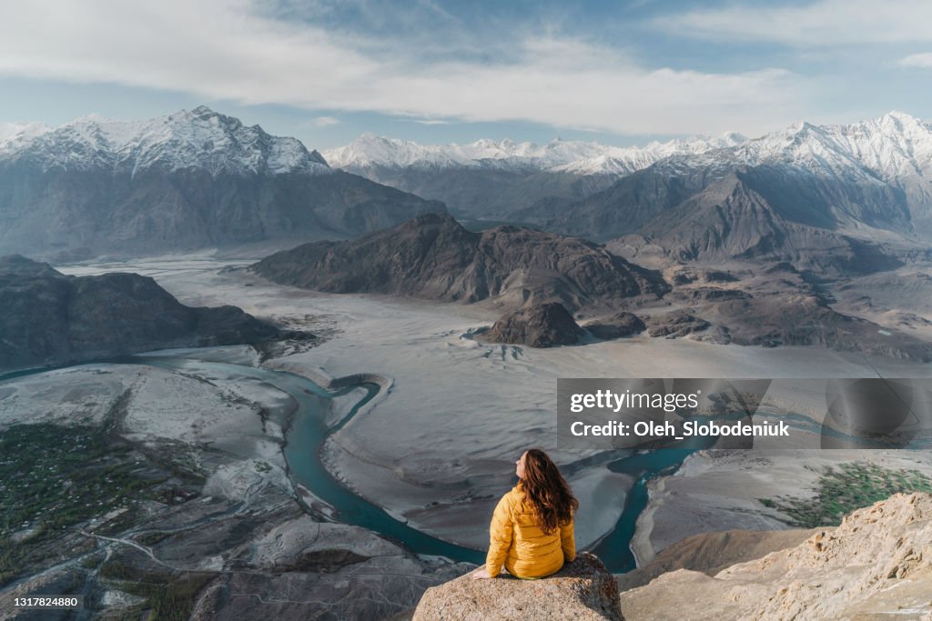 Woman sitting on the edge of hanging rock above the river