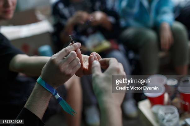 young people pass each other a joint - bracelet ストックフォトと画像