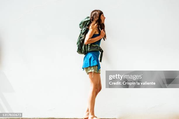 young woman traveler with backpack on white background - pantaloncini bianchi foto e immagini stock