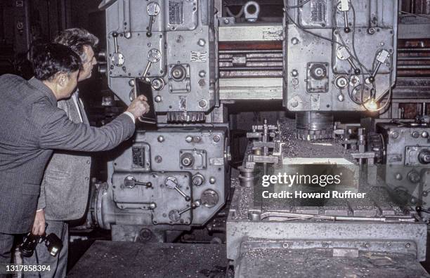 Local foundry supervisor demonstrates a piece of equipment to a visiting American counterpart, China, April 1986.