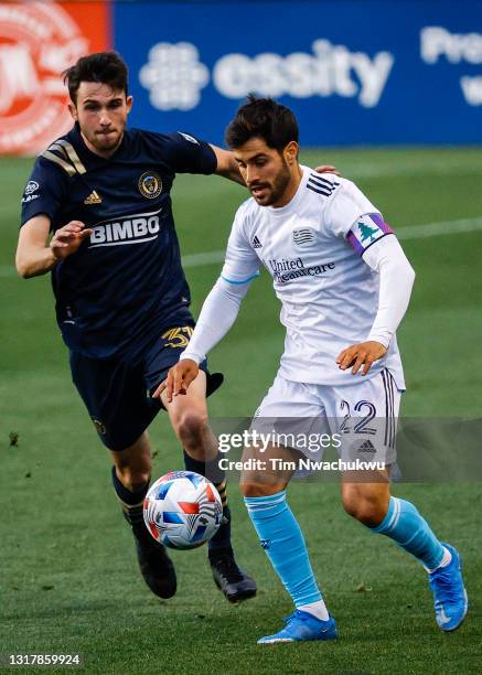 Carles Gil of the New England Revolution dribbles past Leon Flach of the Philadelphia Union during the first half at Subaru Park on May 12, 2021 in...