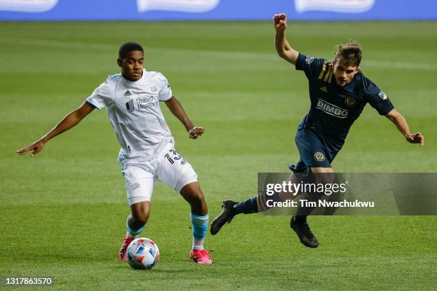 Maciel of the New England Revolution tackles the ball from Leon Flach of the Philadelphia Union during the first half at Subaru Park on May 12, 2021...