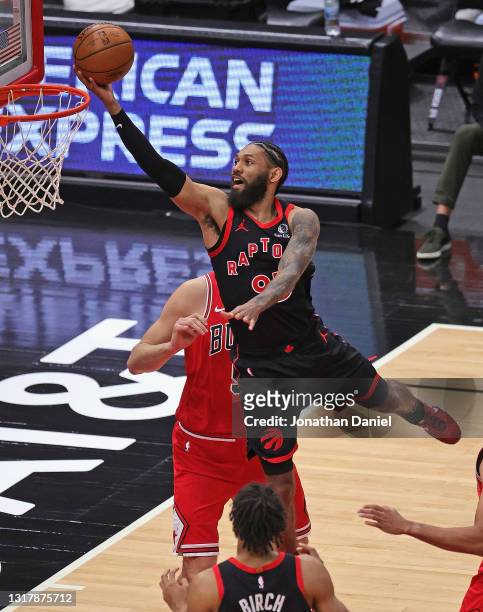 DeAndre' Bembry of the Toronto Raptors lays in a shot over Nikola Vucevic of the Chicago Bulls at the United Center on May 13, 2021 in Chicago,...