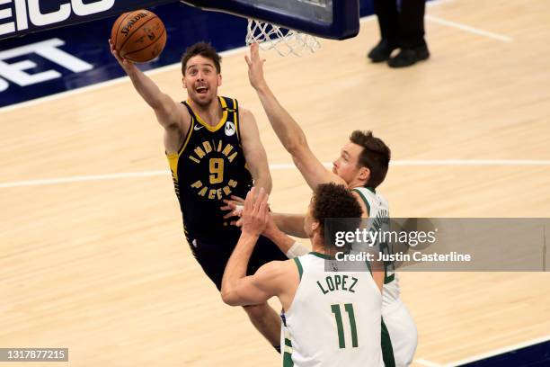 McConnell of the Indiana Pacers takes a shot while guarded by Pat Connaughton and Brook Lopez of the Milwaukee Bucks during the third quarter at...