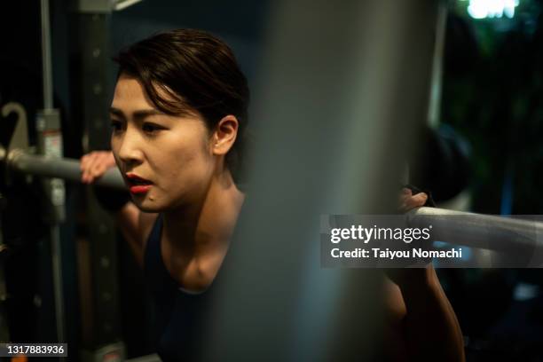 a woman squats with a heavy barbell on her shoulders - asian female bodybuilder 個照片及圖片檔