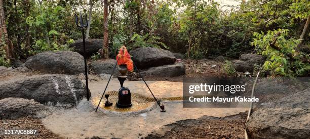 hindu god shiva black marble stone statue amidst rocks and nature - shiva lingam stock pictures, royalty-free photos & images