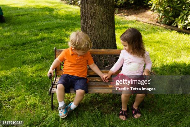 male and female toddler friends holding hands on scaled park bench - girls with short skirts photos et images de collection