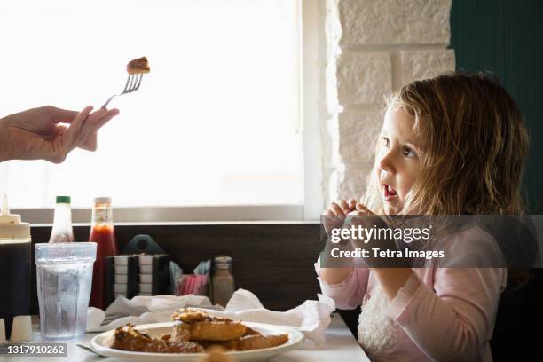 hand of mother feeding toddler daughter in diner - child eat side photos et images de collection