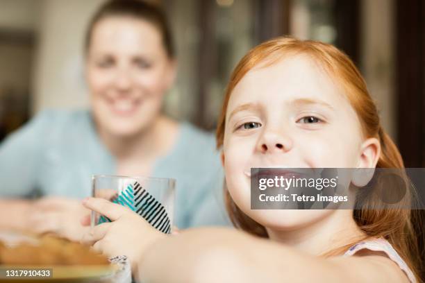 girl with a milk moustache at dining room table - moeder kind zes melk stockfoto's en -beelden