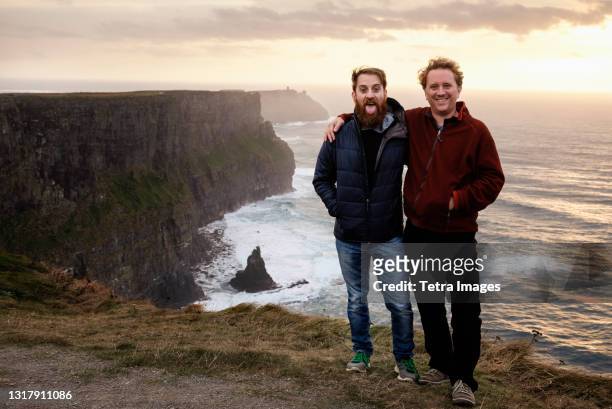 two male friends on the cliffs of moher, the burren, county clare, ireland - irish family stock pictures, royalty-free photos & images