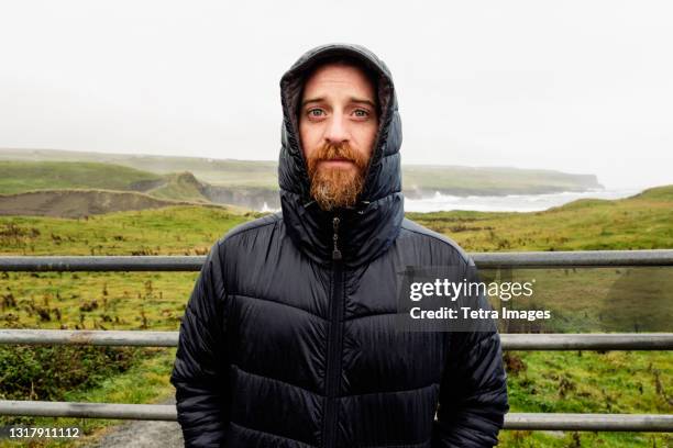 mid adult man wearing winter coat, portrait - padded jacket - fotografias e filmes do acervo