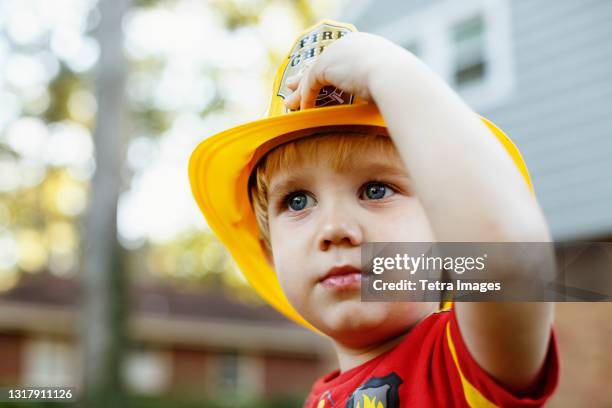 young boy wearing fireman's helmet - boy fireman costume stock pictures, royalty-free photos & images