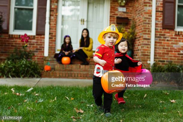 boy dressed as fireman with trick or treat bucket - boy fireman costume stock pictures, royalty-free photos & images