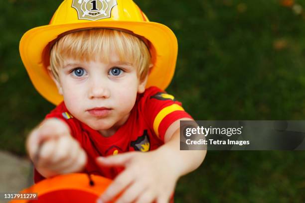 boy wearing fireman's helmet - boy fireman costume stock pictures, royalty-free photos & images