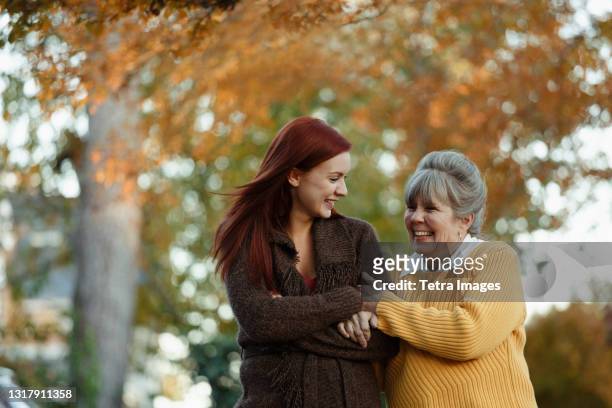 senior woman and adult daughter strolling in suburban park - young woman and senior lady in a park stock pictures, royalty-free photos & images