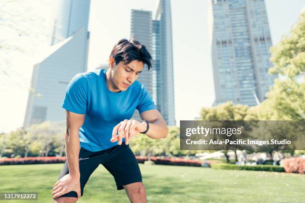 young muscular sportsman man checking data on fitness tracker after training. - asian and indian ethnicities smartwatch phone stock pictures, royalty-free photos & images