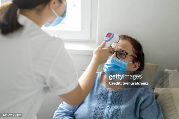 gesundheitspersonal überprüft temperatur auf seniorin - hot nurse stock-fotos und bilder