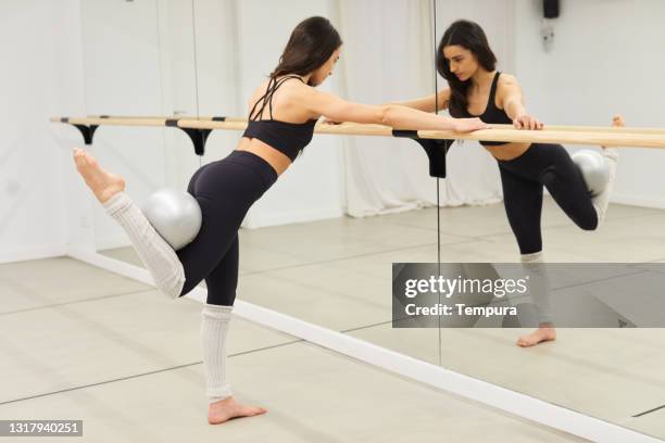 una mujer haciendo ejercicio en un estudio de yoga barre. - barra de deportes fotografías e imágenes de stock