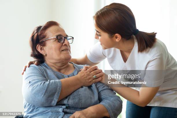 enfermera cariñosa habla con su paciente de edad avanzada - asistencia de la comunidad fotografías e imágenes de stock