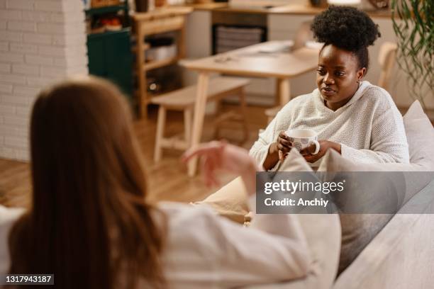 two female friends talk about serious topics over a cup of tea at home - friends serious stock pictures, royalty-free photos & images