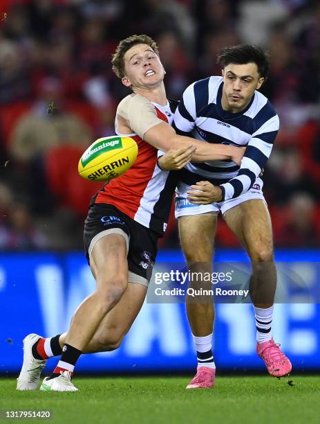 Brad Close of the Cats handballs whilst being tackled by Jack Billings of the Saints during the round 9 AFL match between the St Kilda Saints and the...