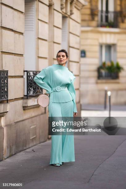 Ketevan Giorgadze @katie.one wears silver earrings, a pale blue oversized belted chiffon lightweight handmade plissé / ribbed long sleeves top with...