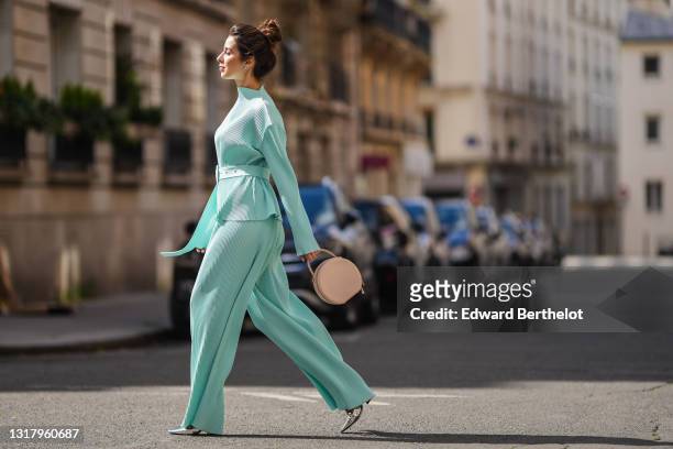 Ketevan Giorgadze @katie.one wears silver earrings, a pale blue oversized belted chiffon lightweight handmade plissé / ribbed long sleeves top with...