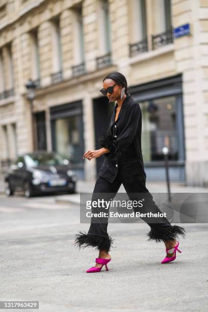 Emilie Joseph @in_fashionwetrust wears silver rhinestones Isabel Marant earrings, black sunglasses, a black ribbed buttoned long shirt with black...