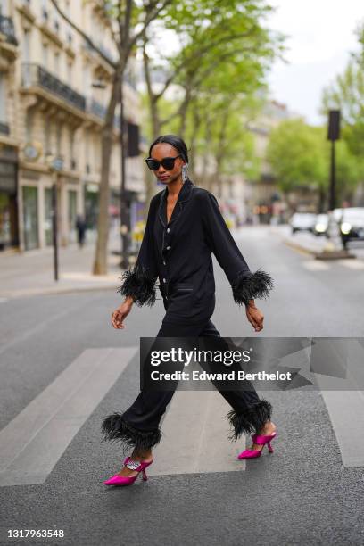 Emilie Joseph @in_fashionwetrust wears silver rhinestones Isabel Marant earrings, black sunglasses, a black ribbed buttoned long shirt with black...