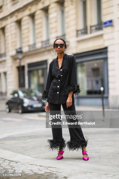 Emilie Joseph @in_fashionwetrust wears silver rhinestones Isabel Marant earrings, black sunglasses, a black ribbed buttoned long shirt with black...