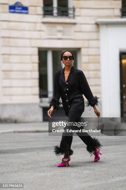 Emilie Joseph @in_fashionwetrust wears silver rhinestones Isabel Marant earrings, black sunglasses, a black ribbed buttoned long shirt with black...